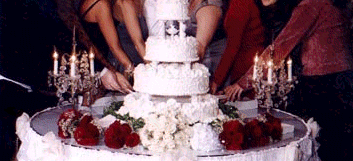 The women have gathered around the wedding cake at the wedding reception to pull the charms from the cake.