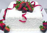 A beautiful charm cake with red ribbons and chocolate dipped strawberries.