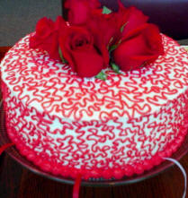This red rose charm cake as red and white satin ribbons with the charms under the bottom of the cake