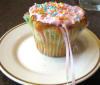 cupcake with pink icing and a charm inserted under the icing for the bridesmaid