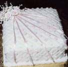 The cake charms on this bridesmaid's charm cake are under the flowers in the top left corner with the ribbons across the cake.